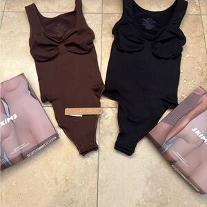 Stylish SKIMS bodysuits in black thong design .
